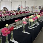 Vue des tables avec des fleurs de pivoines coupées dans des vases lors du Grand Bal 2023