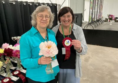 Sylvie Perron présentant à Céline Arseneault (en l'absence de Kate-Lynn Clark, En Fleurs) le ruban gagnant pour Semi-double (ex-aequo) : Blushing Princess, classe 1