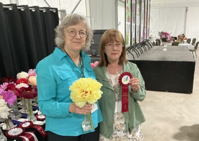 Sylvie Perron présentant à Jocelyn Leblanc le ruban gagnant pour la pivoine intersectionnelle double : Sonoma Yedo, classe 2