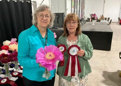 Sylvie Perron présentant à Lucie Pepin, en l'absence de Faustino Amigo, le ruban gagnant pour Gordon E. Simonson, pivoine Itoh semi-double classe 2, également grande gagnante, avec ruban rosette