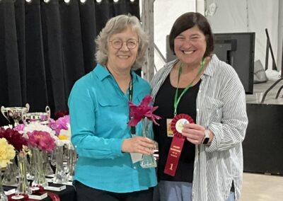 Sylvie Perron présentant à Céline Arseneault le ruban gagnant pour Port Royale, pivoine japonaise classe 2