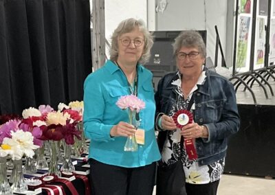 Sylvie Perron présentant à Lise Rondeau le ruban gagnant pour Illini Petite Elegance, pivoine semi-double classe 2
